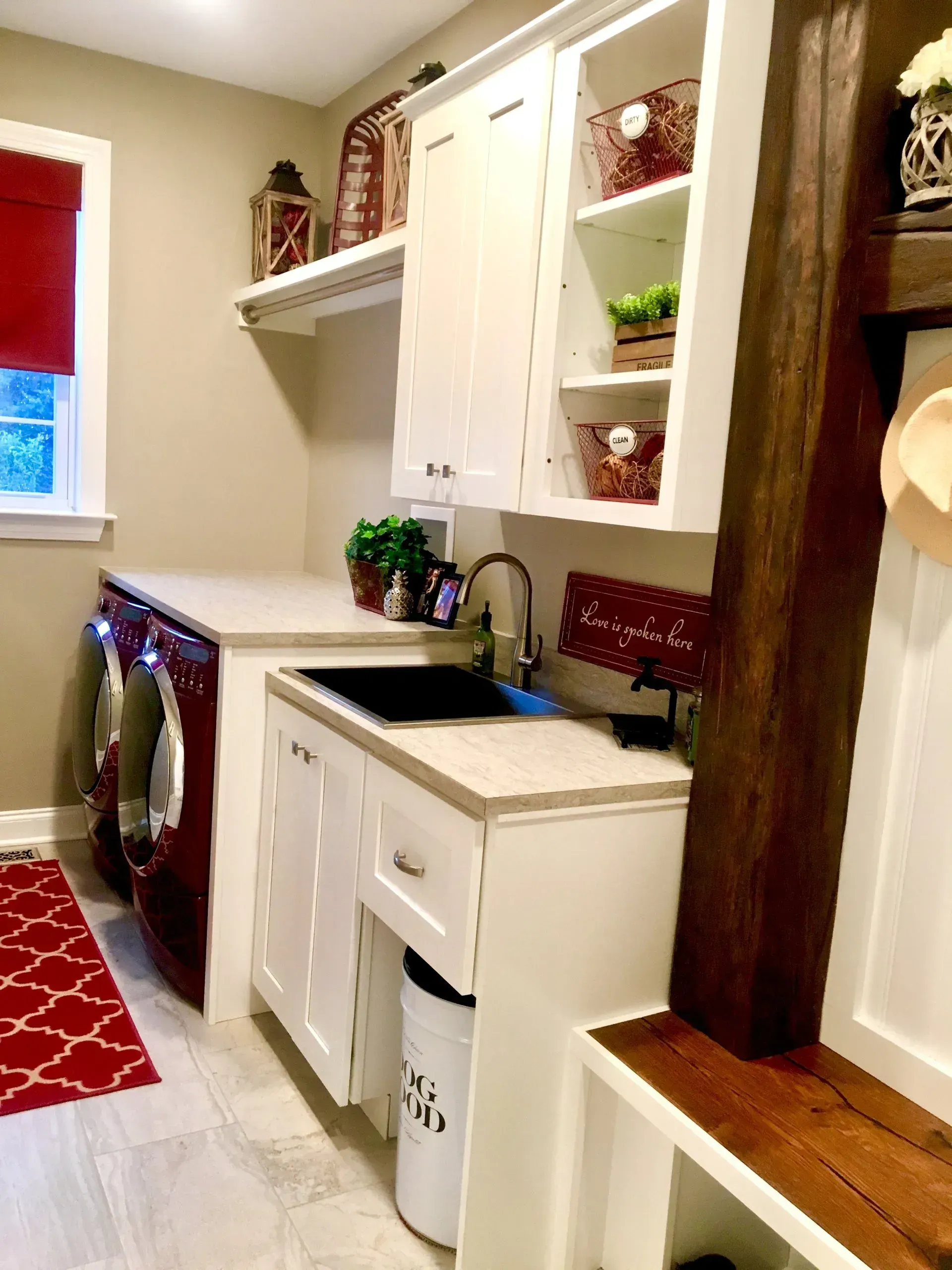 Bright kitchen with white cabinets, red rug, sink, and shelves beside a wooden post In Bucks County PA