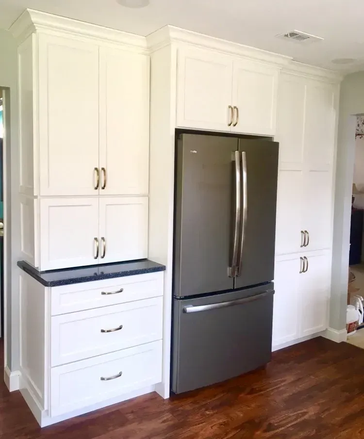White kitchen cabinets with stainless steel refrigerator and dark wood floor In Bucks County PA