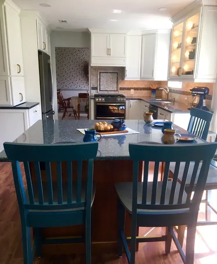 Bright kitchen with teal island chairs, white cabinets, and a stove centered in the background In Bucks Country PA