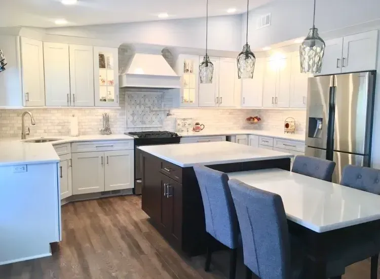 Modern white kitchen with island, pendant lights, stainless-steel appliances, and two gray bar stools In Bucks Country PA