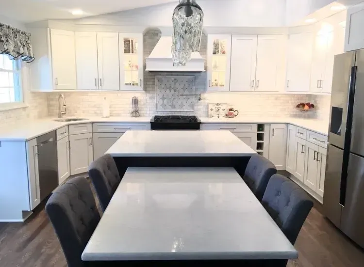 Bright white kitchen with large island, gray cabinets, black stools, and stainless steel appliances In Bucks Country PA