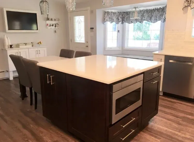 Modern kitchen with a dark island, barstools, stainless appliances, and a large window with curtains In Bucks Country PA