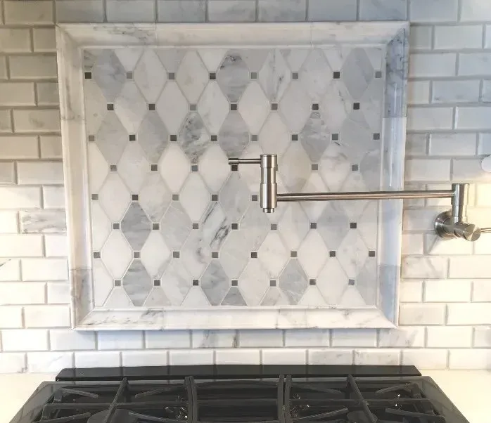 Built-in marble-look tile niche with a metal arm above a kitchen stove under white subway tile backsplash In Bucks Country PA