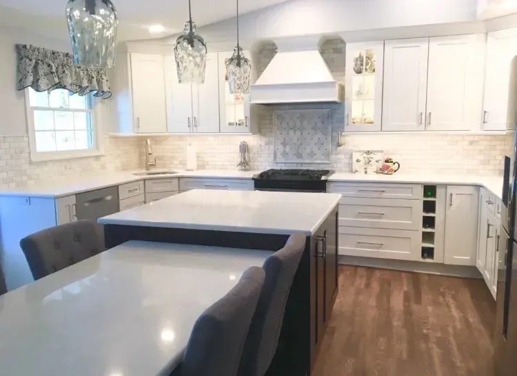 Bright modern kitchen with white cabinets, black island, and gray upholstered chairs In Bucks Country PA