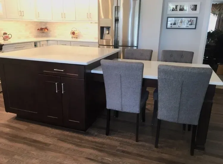 Modern kitchen with dark island, white countertops, and two gray chairs on a wood floor In Bucks Country PA