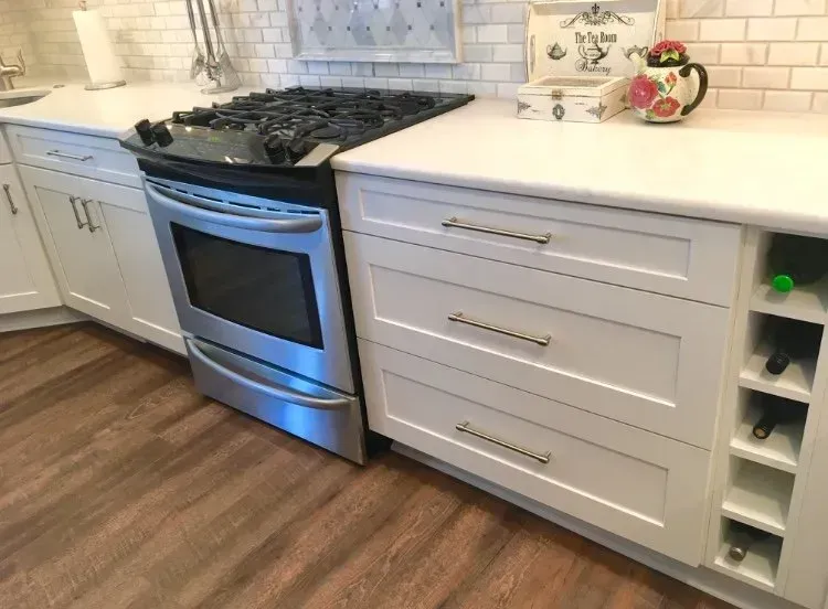Modern kitchen with stainless steel stove and white cabinets on wood flooring In Bucks Country PA