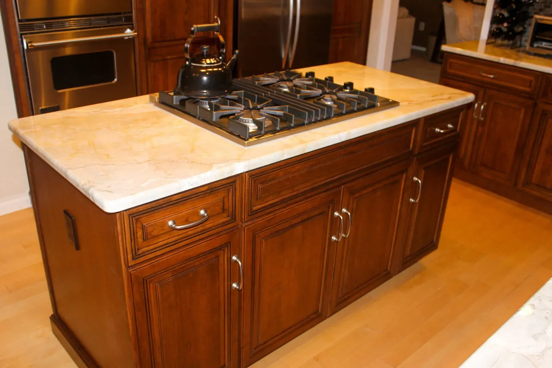 Wooden kitchen island with beige countertop and built-in gas cooktop in a modern kitchen In Bucks Country PA