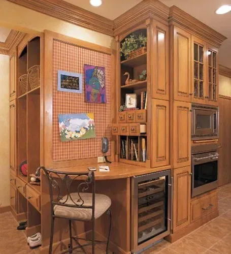 Warm wood kitchen with built-in cabinets, wine fridge, bar seating, and colorful wall art  In Bucks County PA