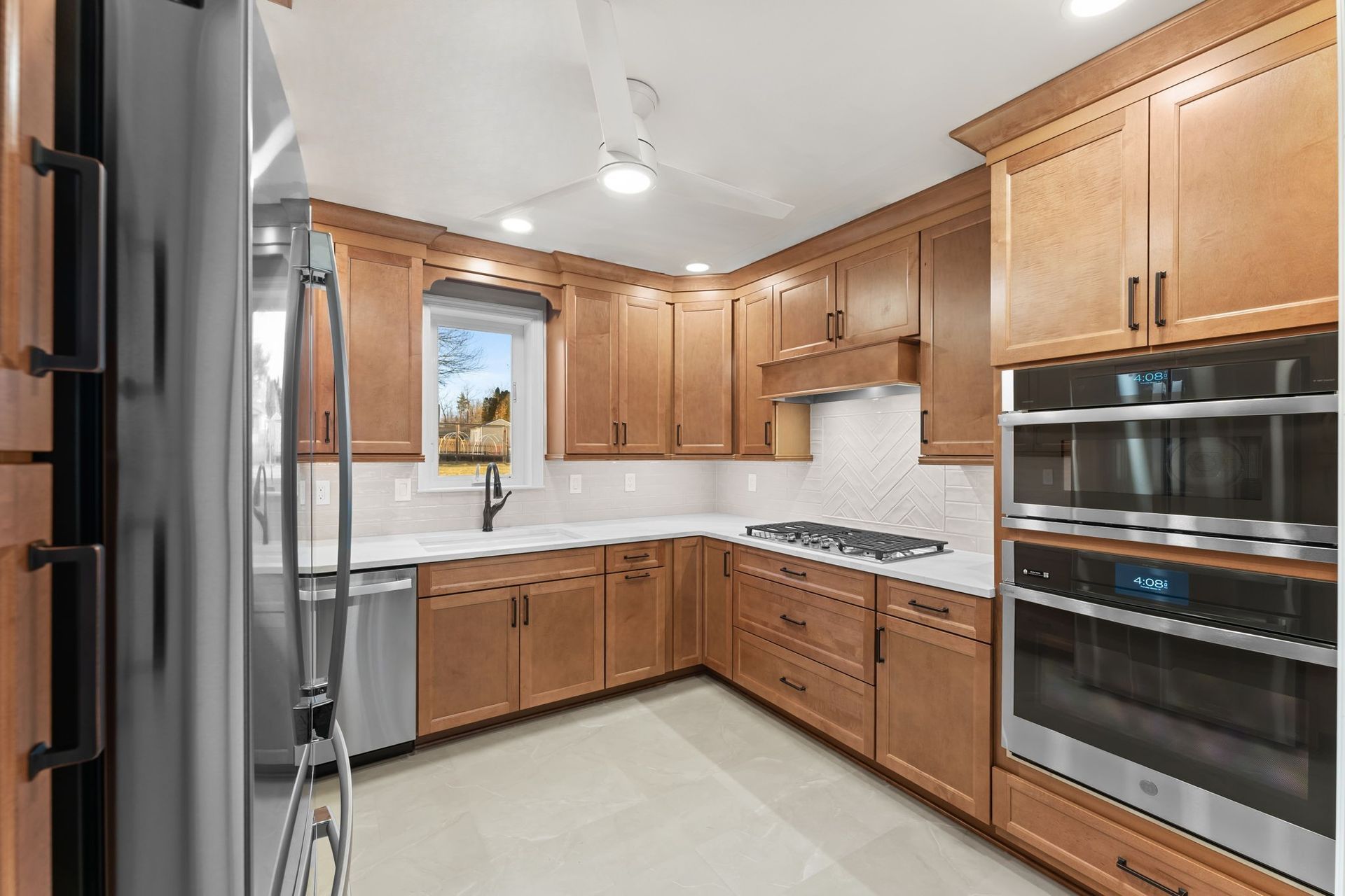 Modern kitchen with wood cabinets, stainless appliances, white countertops, and a window over the sink  In Bucks County PA