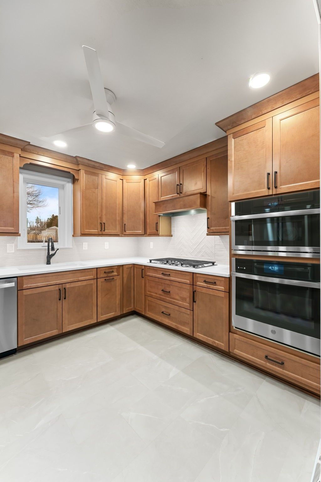 Spacious modern kitchen with light wood cabinets, white tile floor, and stainless steel appliances  In Bucks County PA