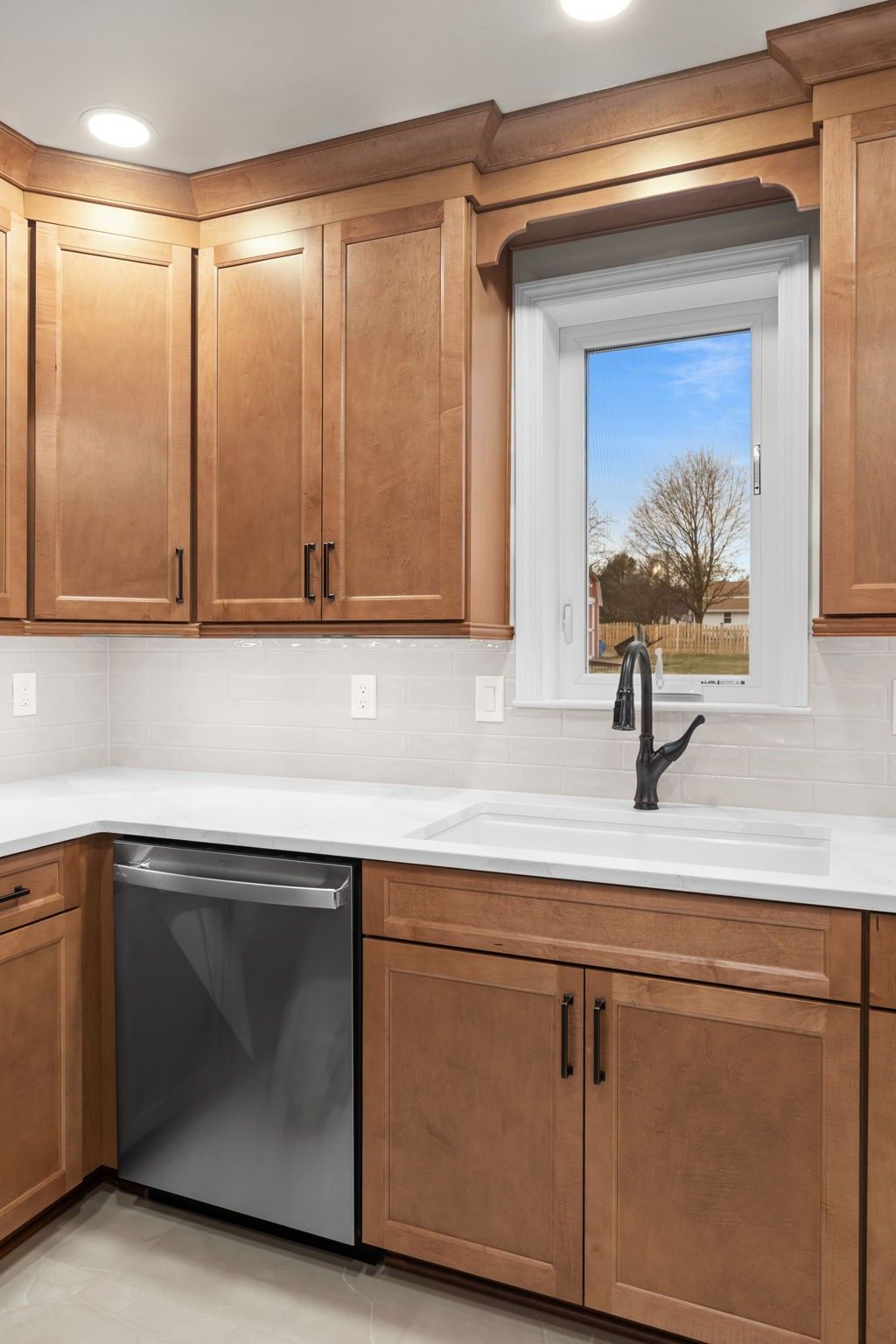 Kitchen with wood cabinets, white countertops, stainless dishwasher, and a window over the sink  In Bucks County PA