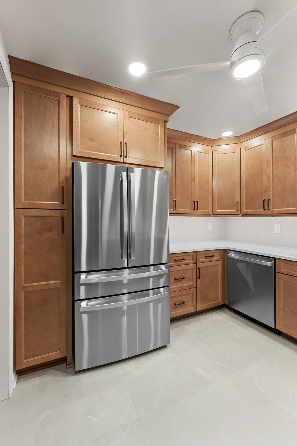 Modern kitchen with stainless steel refrigerator, wood cabinets, dishwasher, and light tile floor  In Bucks County PA