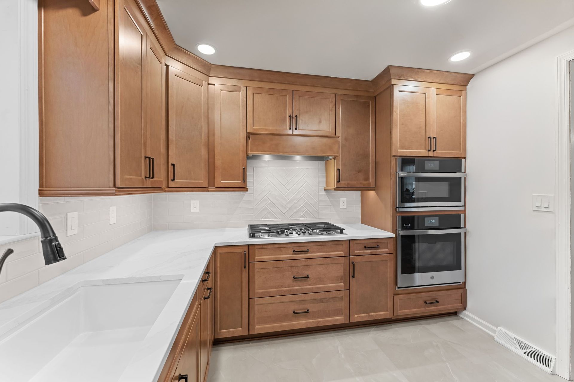 Bright modern kitchen with light wood cabinets, white countertops, double sink, and built-in oven  In Bucks County PA