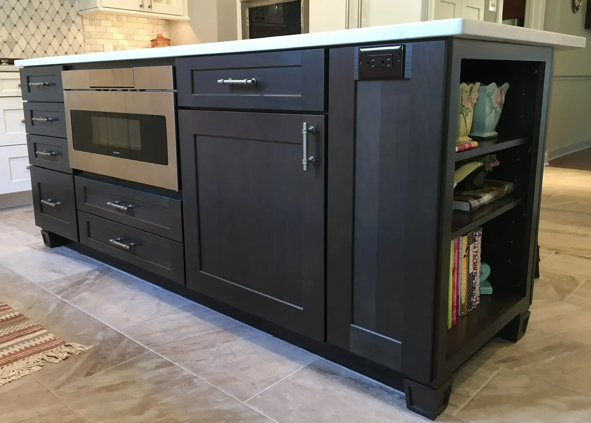 Dark kitchen island with built-in oven, cabinets, and open shelving on the right In Bucks County PA