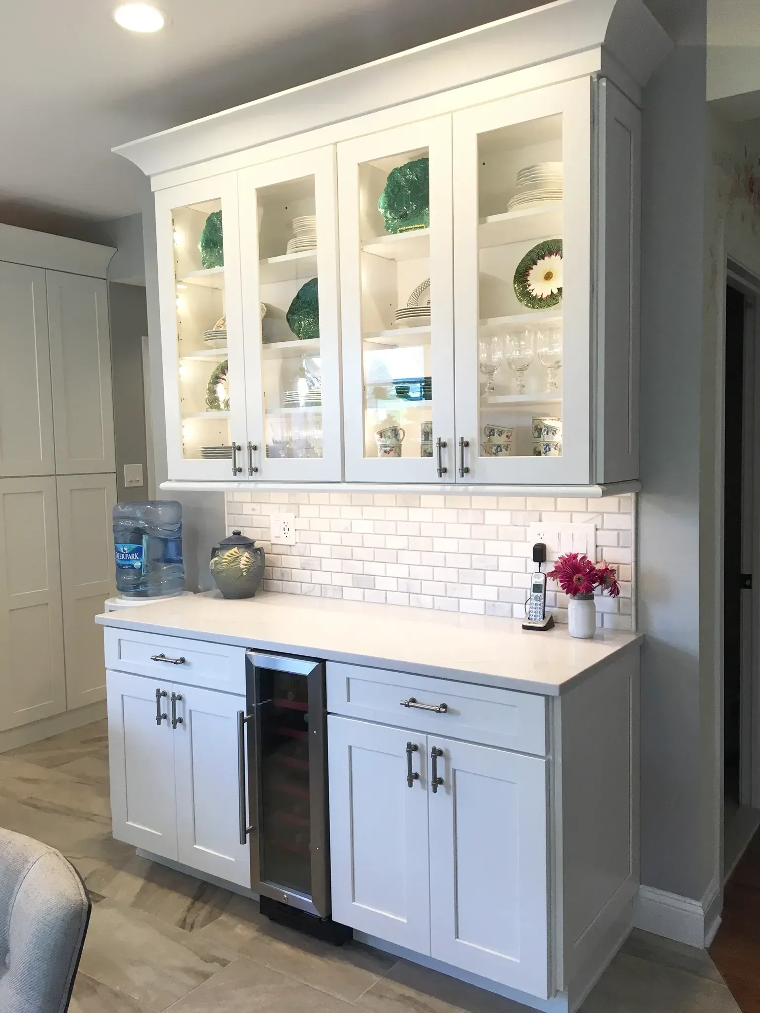 Built-in white cabinet with glass display doors, countertop, and tiled backsplash in a bright kitchen nook In Bucks County PA