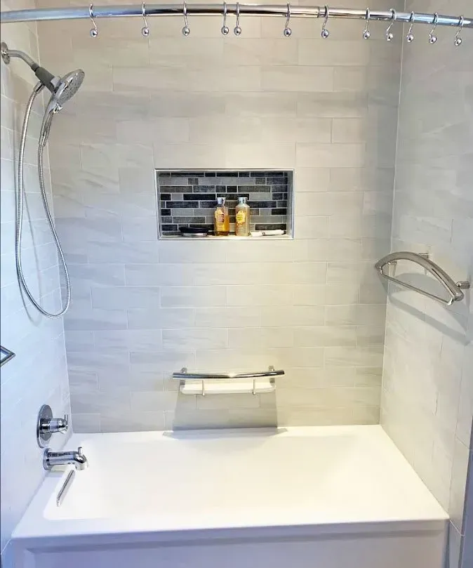 Accessible bathroom shower with grab bars, bench, handheld shower, and built-in wall shelf In Bucks Country PA