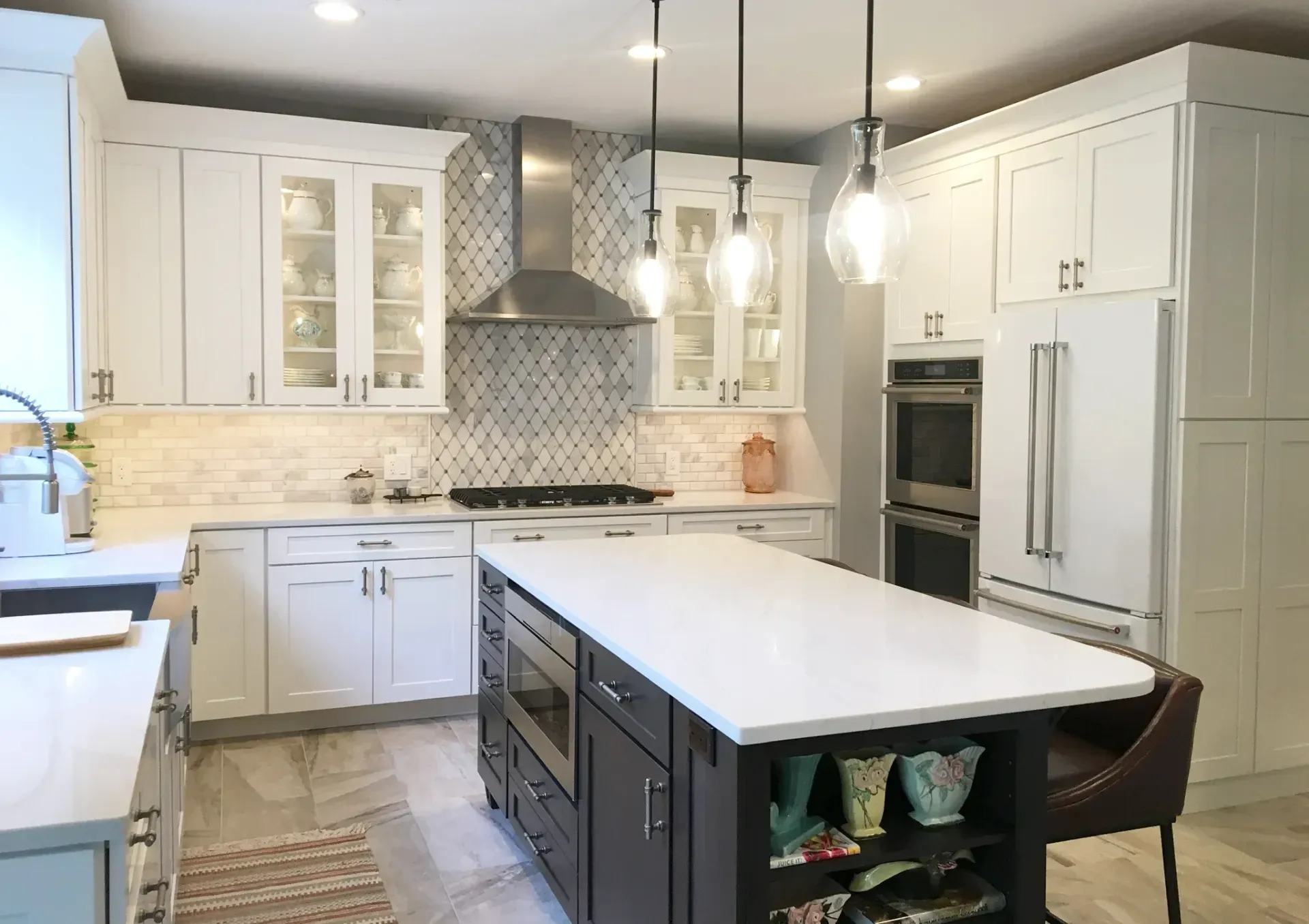 Modern white kitchen with island, pendant lights, stainless steel appliances, and patterned tile backsplash In Bucks Country PA