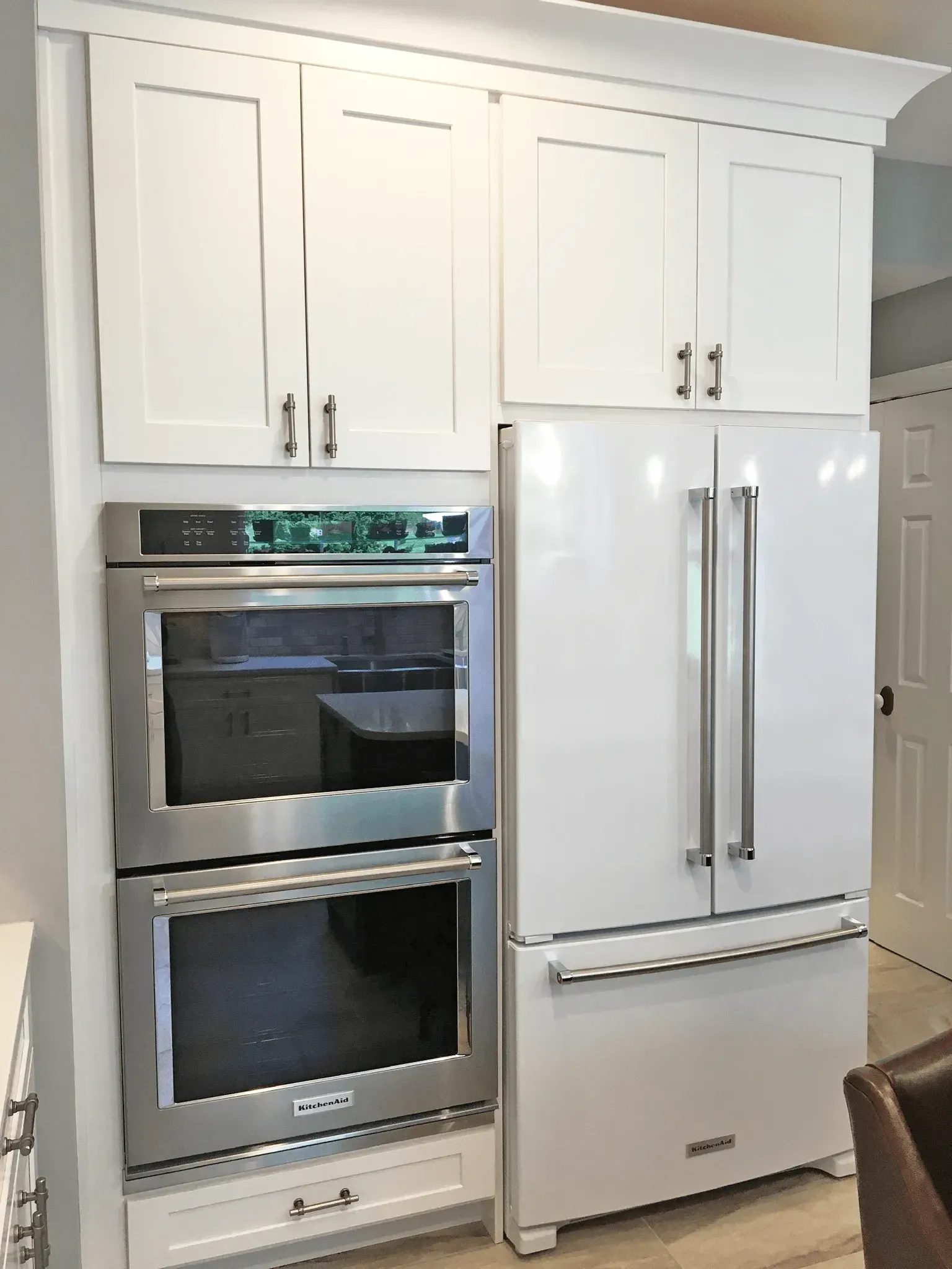 White kitchen with built-in double oven, white cabinets, and stainless steel refrigerator In Bucks County PA