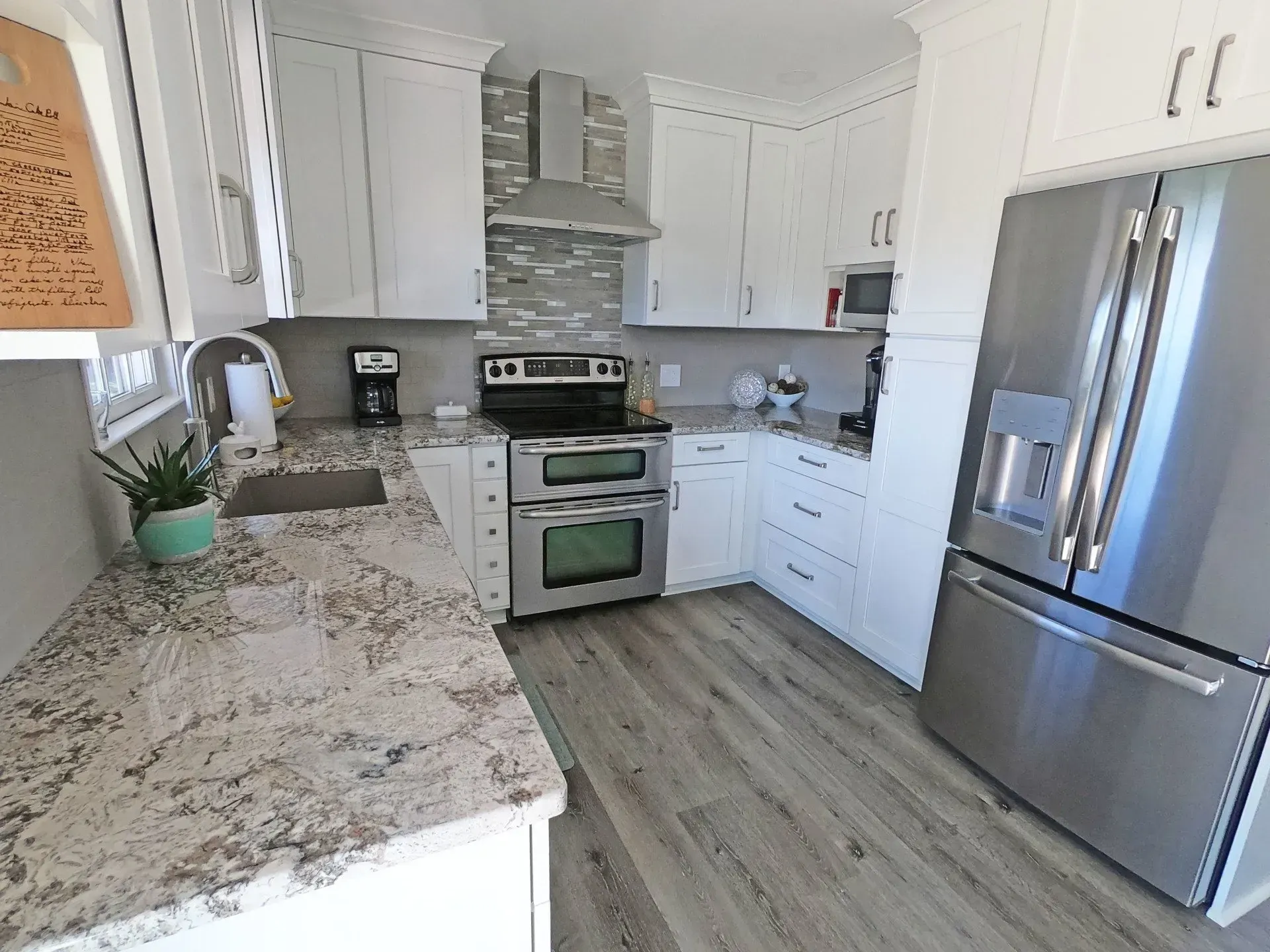 Bright modern kitchen with white cabinets, stainless steel appliances, and gray granite counters In Bucks County PA