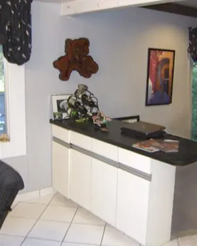 Modern kitchen counter with white cabinets, dark countertop, decor, and tiled floor in a home interior in Bucks County PA