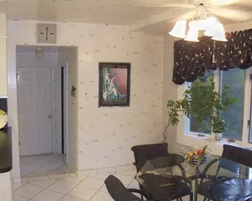 Small dining area with glass table, black chairs, hanging light, window plant, and hallway doorway in Bucks County PA