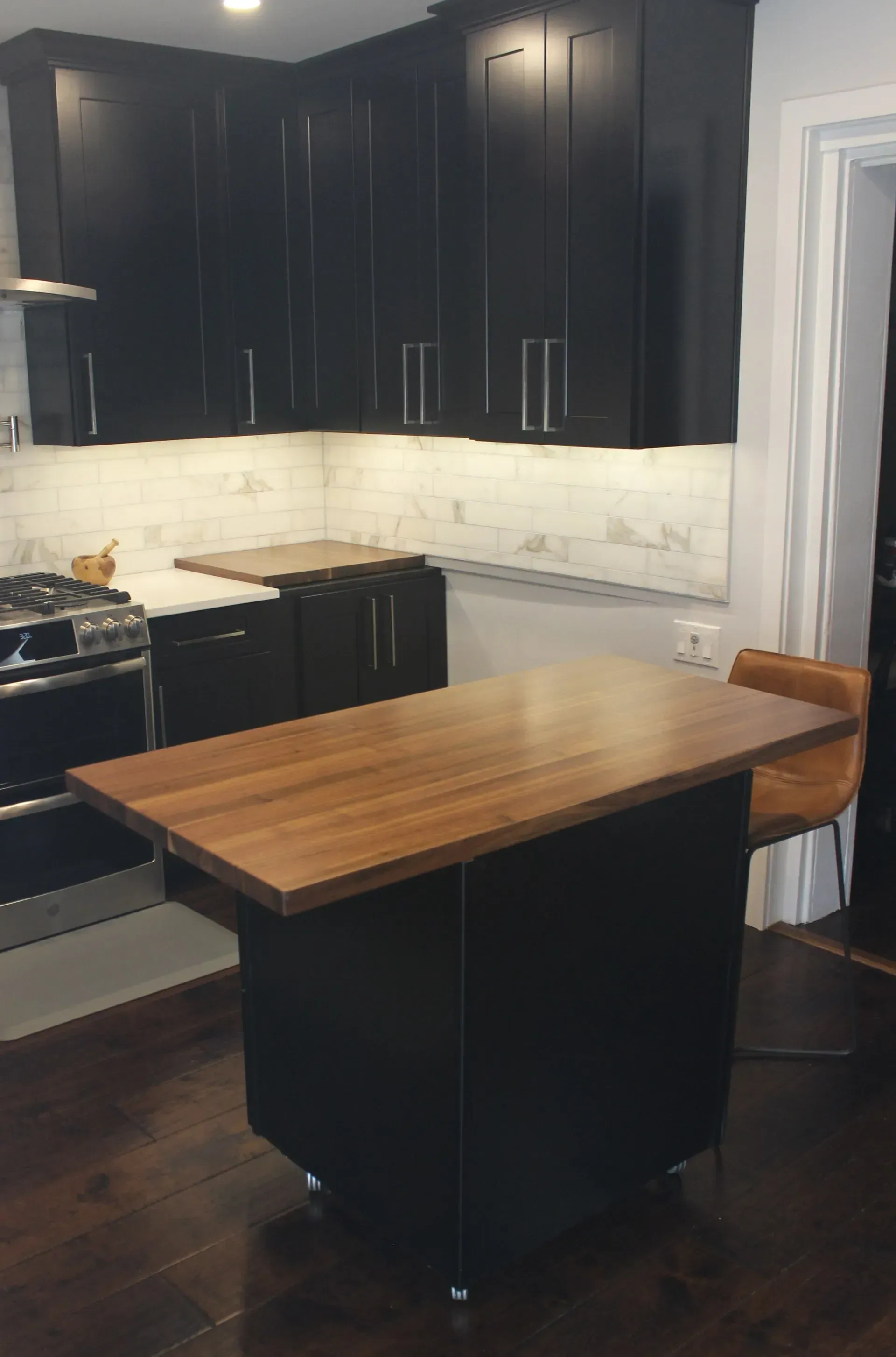 Modern kitchen with dark cabinets, marble backsplash, and a wood-topped island in Bucks County PA