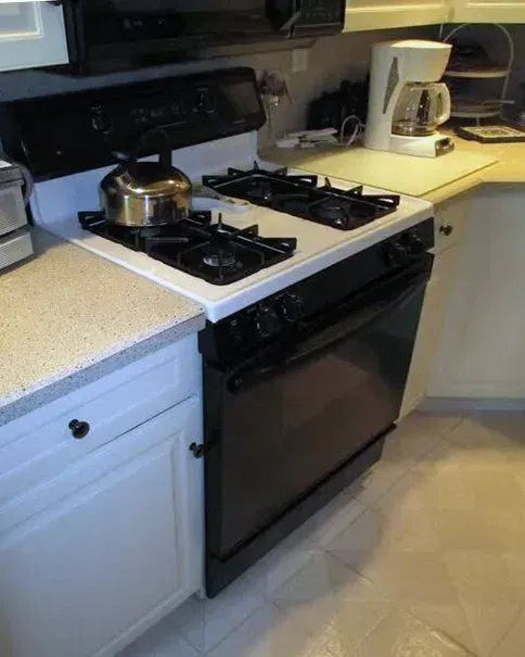 Black gas stove with pot in a kitchen, next to a white coffee maker on a countertop  In Bucks County PA