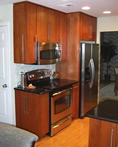 Compact kitchen with cherry cabinets, stainless steel appliances, and black countertops. In Bucks County PA 