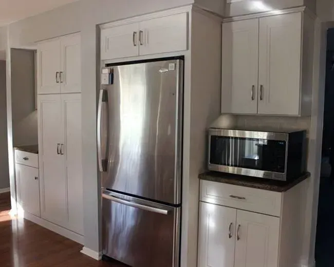 White kitchen with stainless steel fridge, built-in microwave, and cabinets along a wall  In Bucks County PA