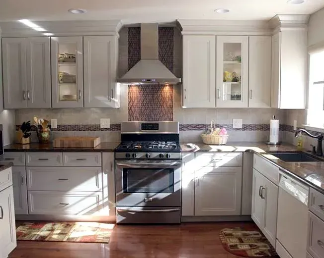 Bright white kitchen with stainless steel stove, dark countertops, and sunlight streaming through windows In Bucks Country PA