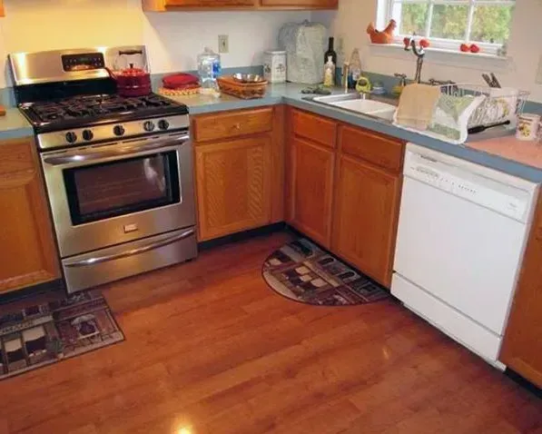 Bright kitchen with stainless stove, wooden cabinets, white dishwasher, and hardwood floor  In Bucks County PA