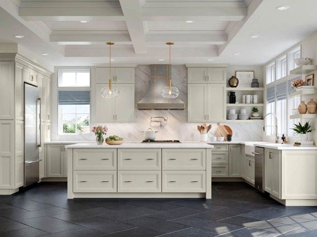 Bright white kitchen with a large island, black floor tiles, and stainless steel range hood In Bucks County PA