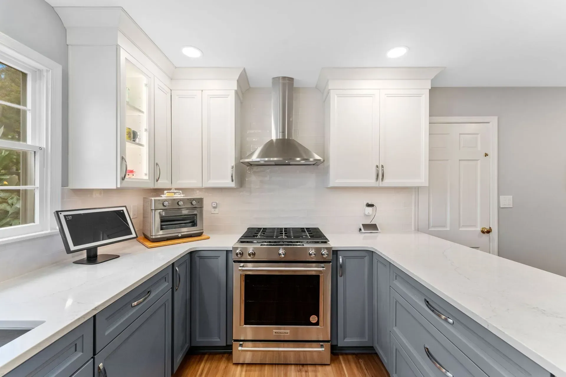 Bright modern kitchen with white and blue cabinets, stainless steel stove, and large white island countertops In Bucks Country PA