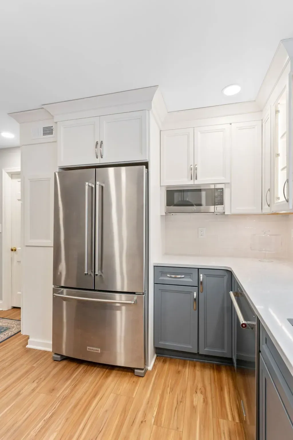 Bright kitchen with stainless steel fridge, microwave, white cabinets, and blue lower cabinets In Bucks Country PA