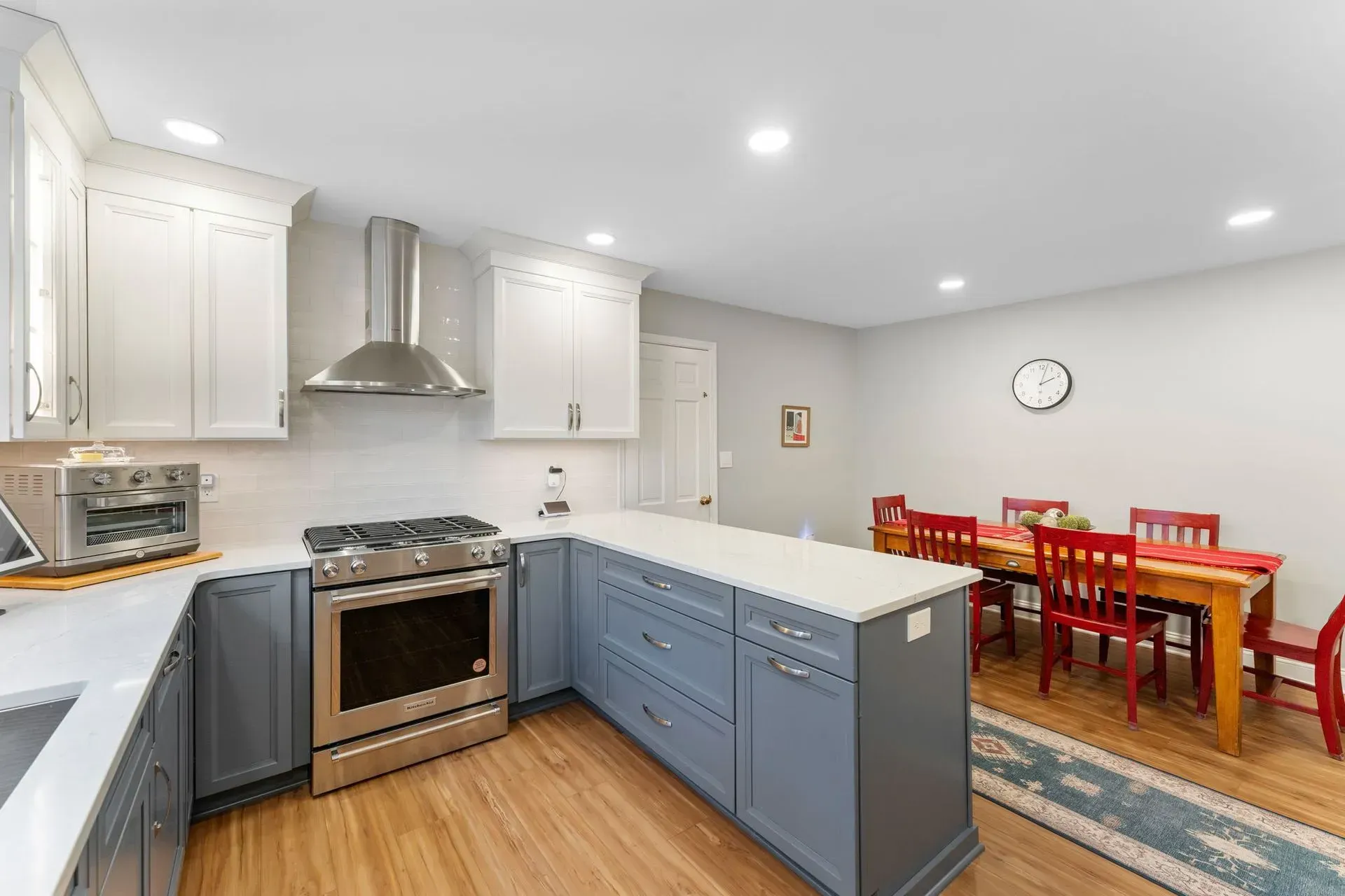 Bright kitchen with blue island, white cabinets, stainless stove, and red dining table with chairs In Bucks Country PA
