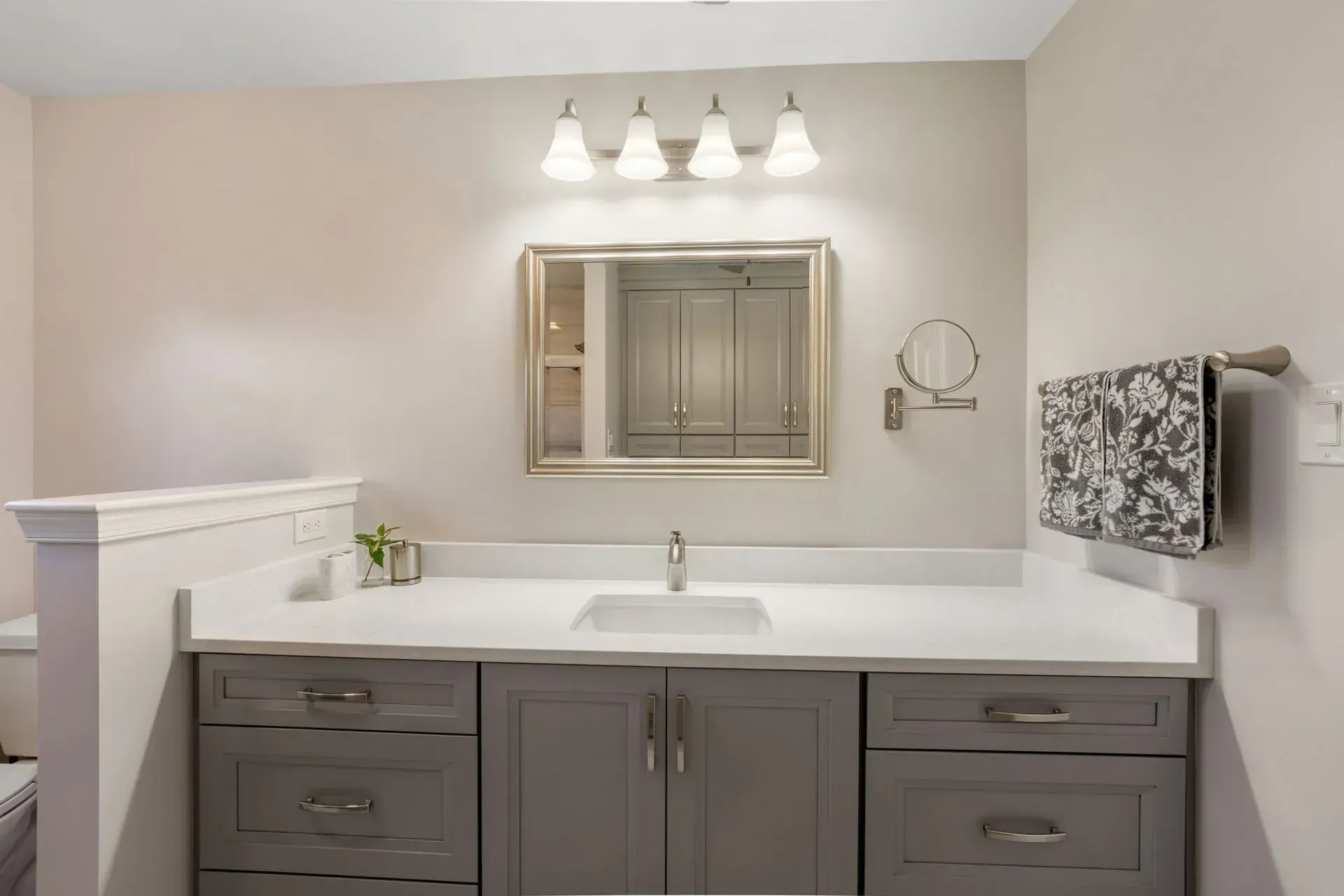 Modern bathroom vanity with gray cabinets, white countertop, mirror, lights, and towel rack In Bucks County PA