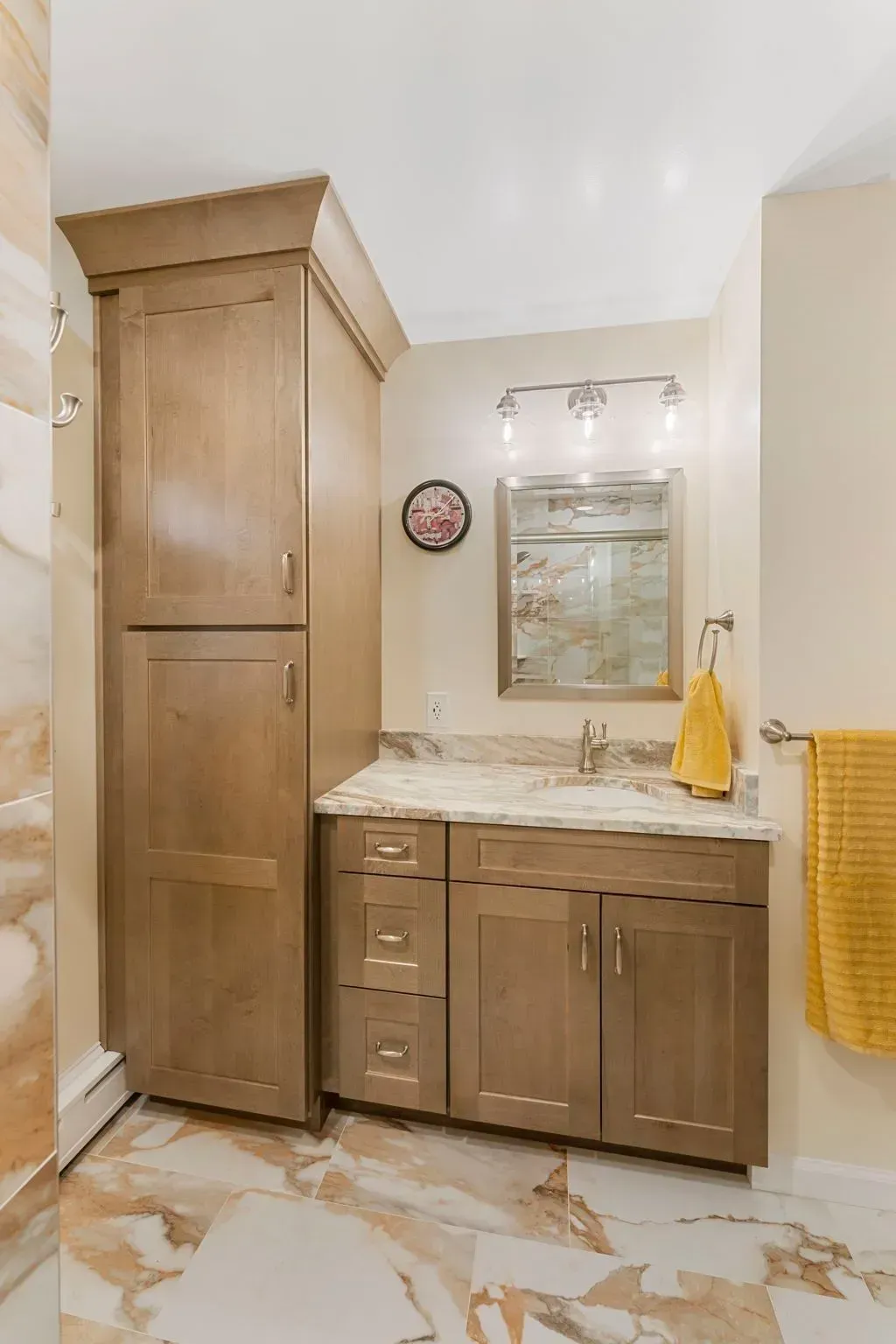Small bathroom with wood vanity, marble countertop, mirror, and towel rack In Bucks County PA