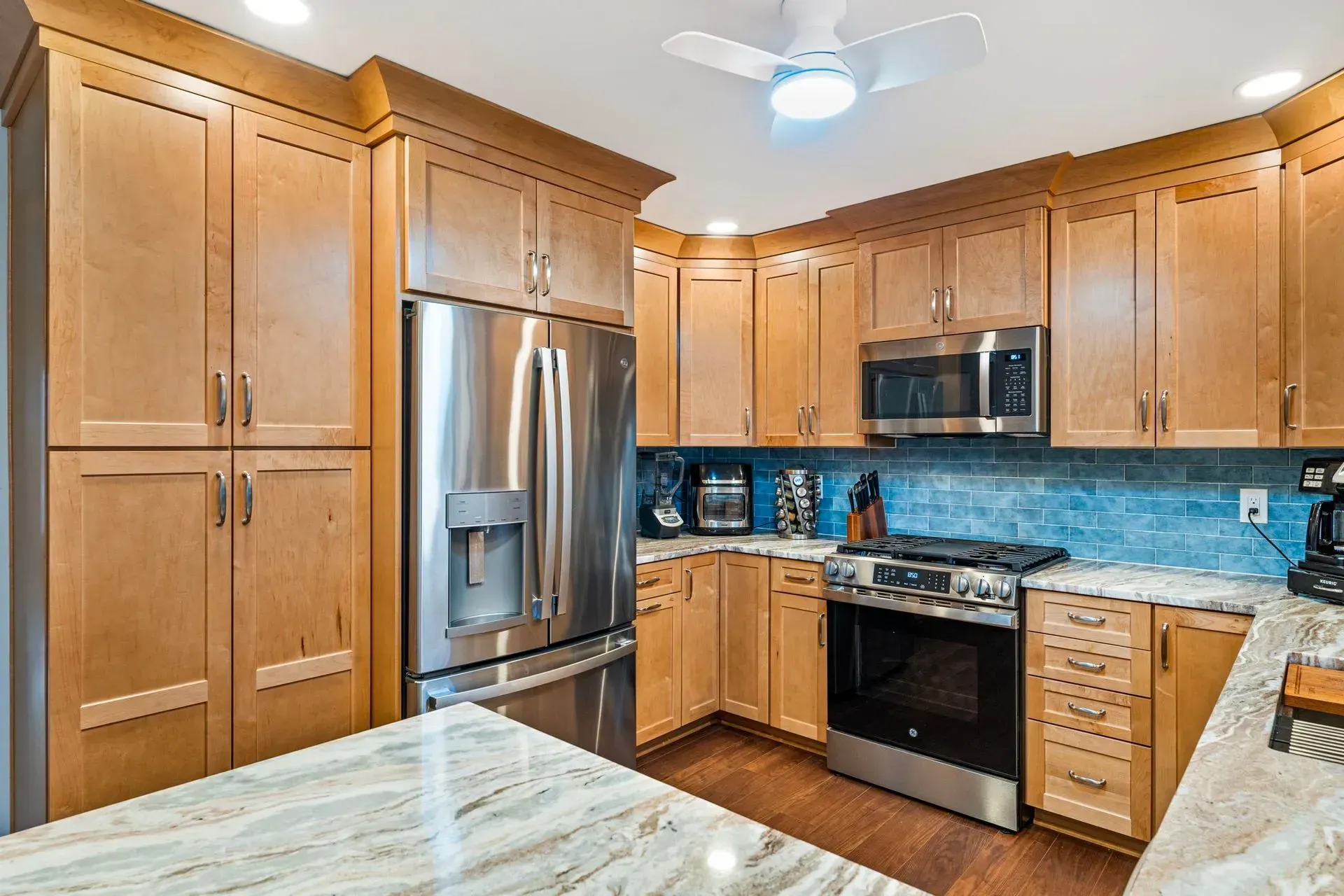 Bright modern kitchen with wood cabinets, stainless steel appliances, blue tile backsplash, and granite countertops In Bucks Country PA