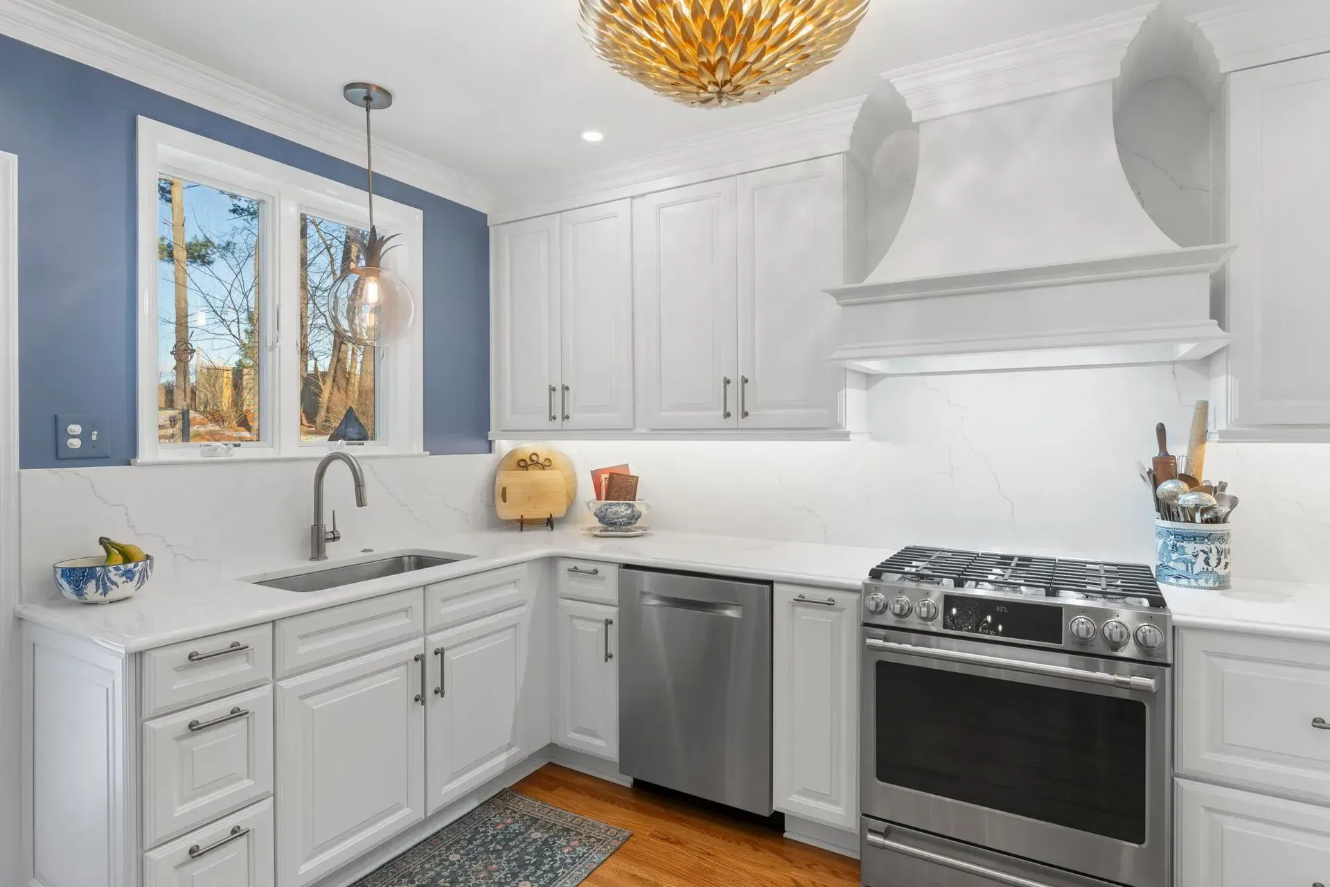 Bright white kitchen with gray cabinets, stainless appliances, and a large window over the sink In Bucks Country PA