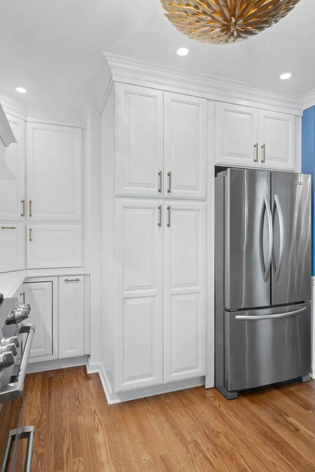 White kitchen with tall cabinets and stainless steel refrigerator over hardwood floor  In Bucks County PA