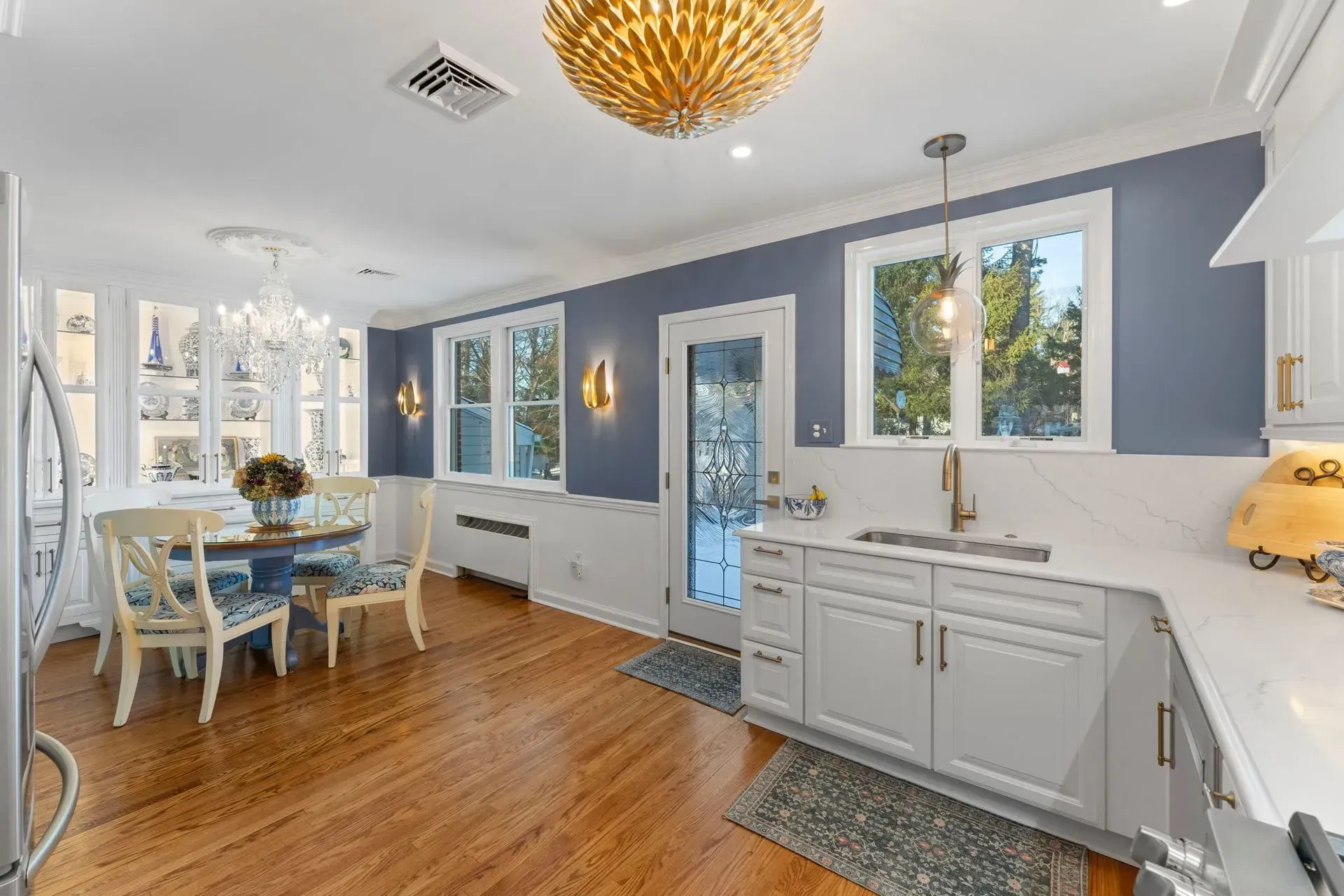 Bright kitchen with white cabinets, blue walls, hardwood floors, and a dining nook by the window  In Bucks County PA
