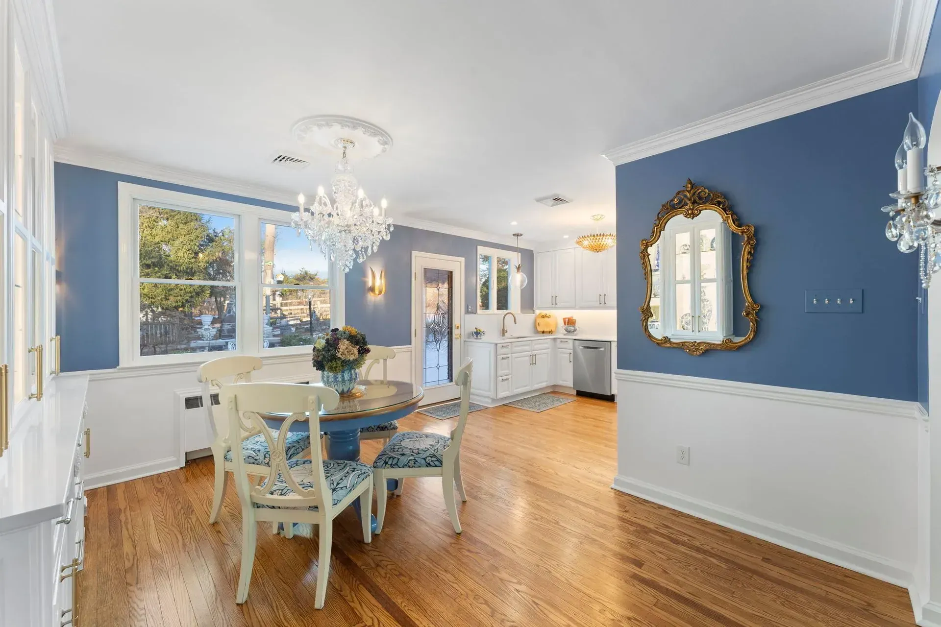 Bright dining room with blue walls, chandelier, wooden floors, and a table near large windows  In Bucks County PA