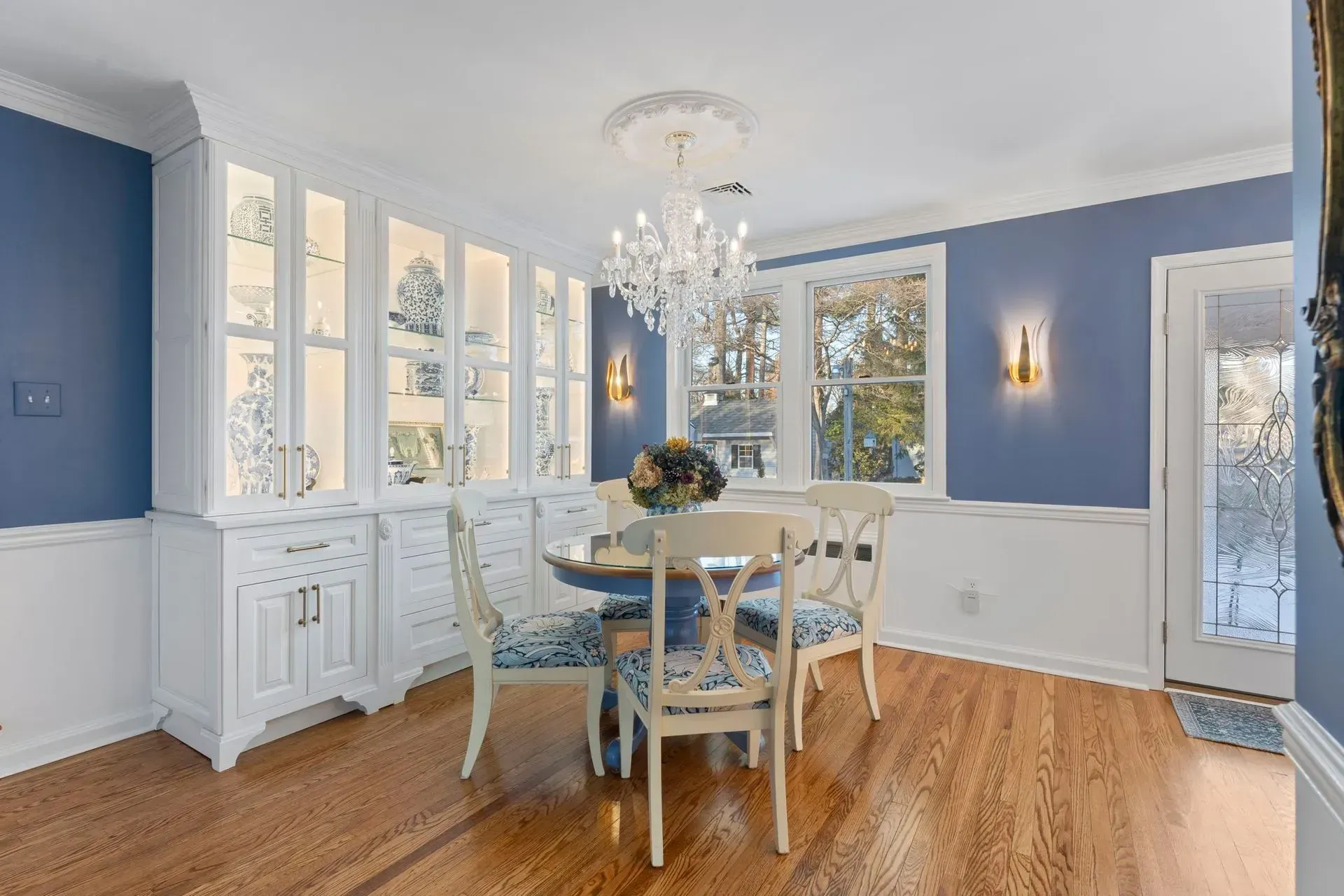 Blue dining room with white trim, chandelier, and table by large windows  In Bucks County PA