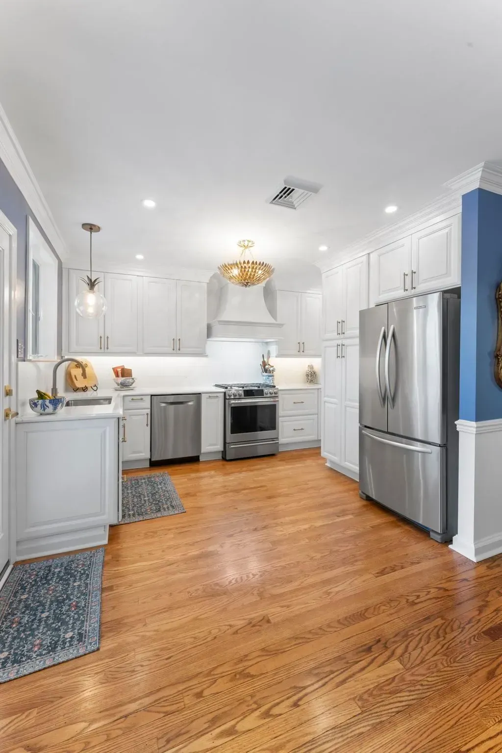Bright white kitchen with stainless steel appliances, hardwood floors, and blue accent walls  In Bucks County PA