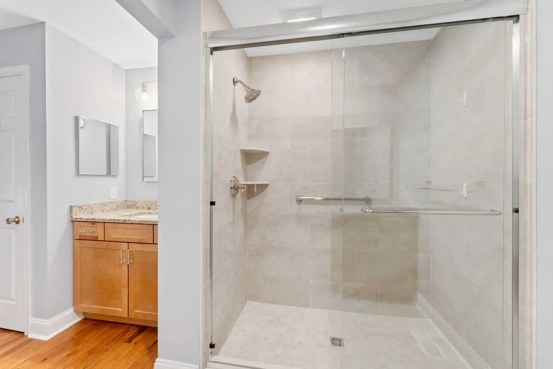 Bathroom with a glass-enclosed walk-in shower, beige tile, and a vanity with wood cabinets beside it in Bucks County PA