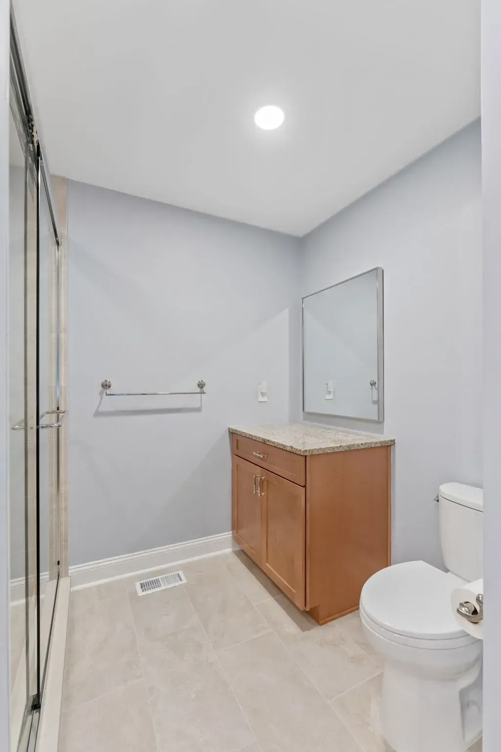 Small bathroom with shower, vanity, mirror, toilet, and light gray walls in Bucks County PA