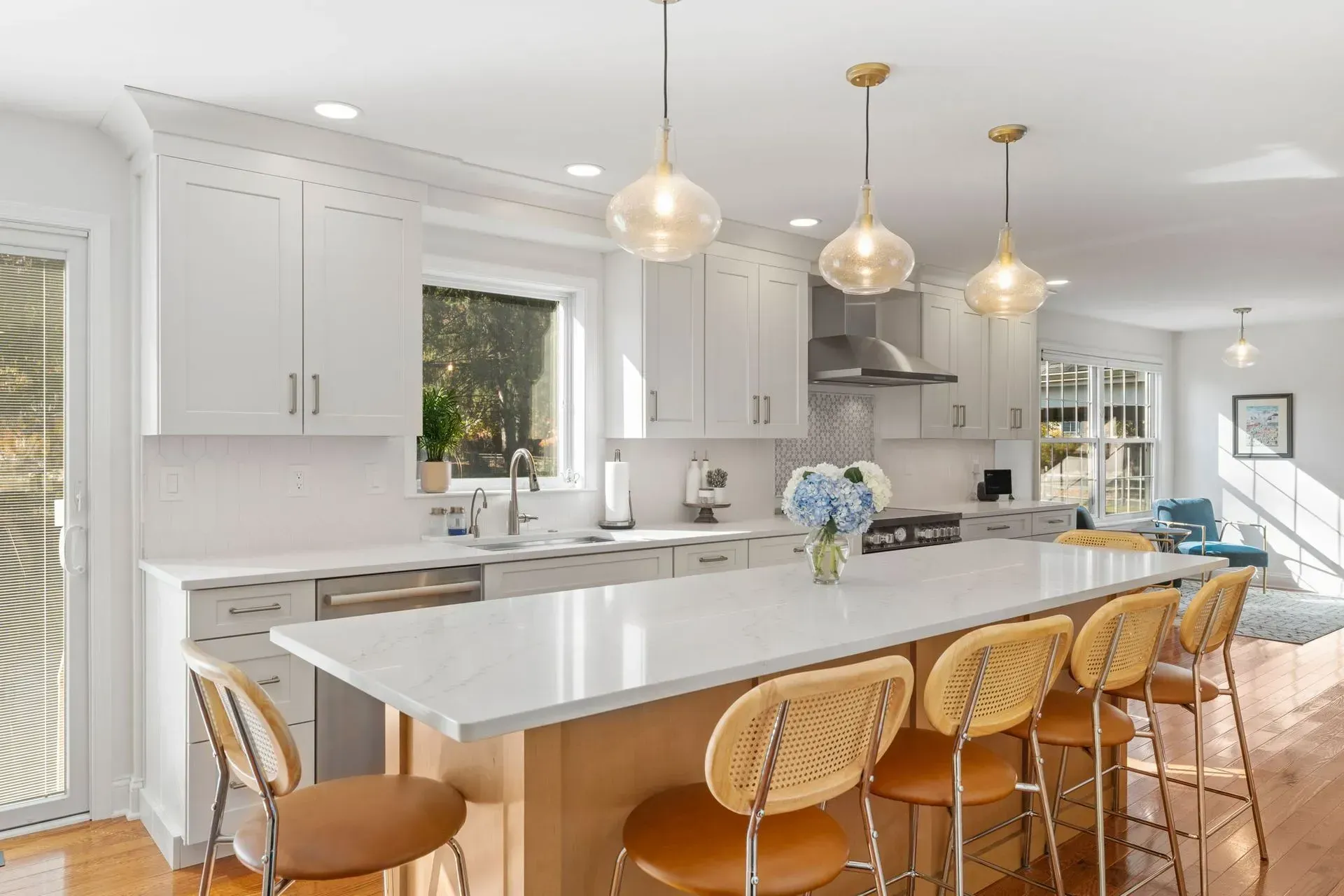 Bright white kitchen with marble island, wicker stools, and pendant lights In Bucks County PA