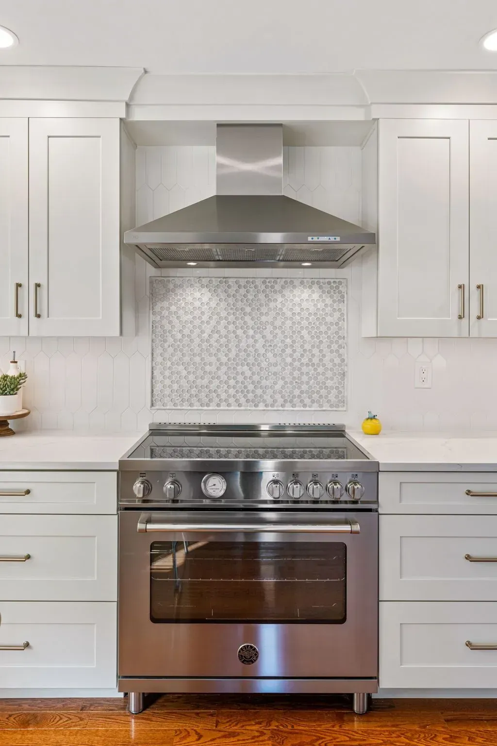 Modern kitchen with white cabinets, stainless steel stove, and decorative tile backsplash In Bucks County PA