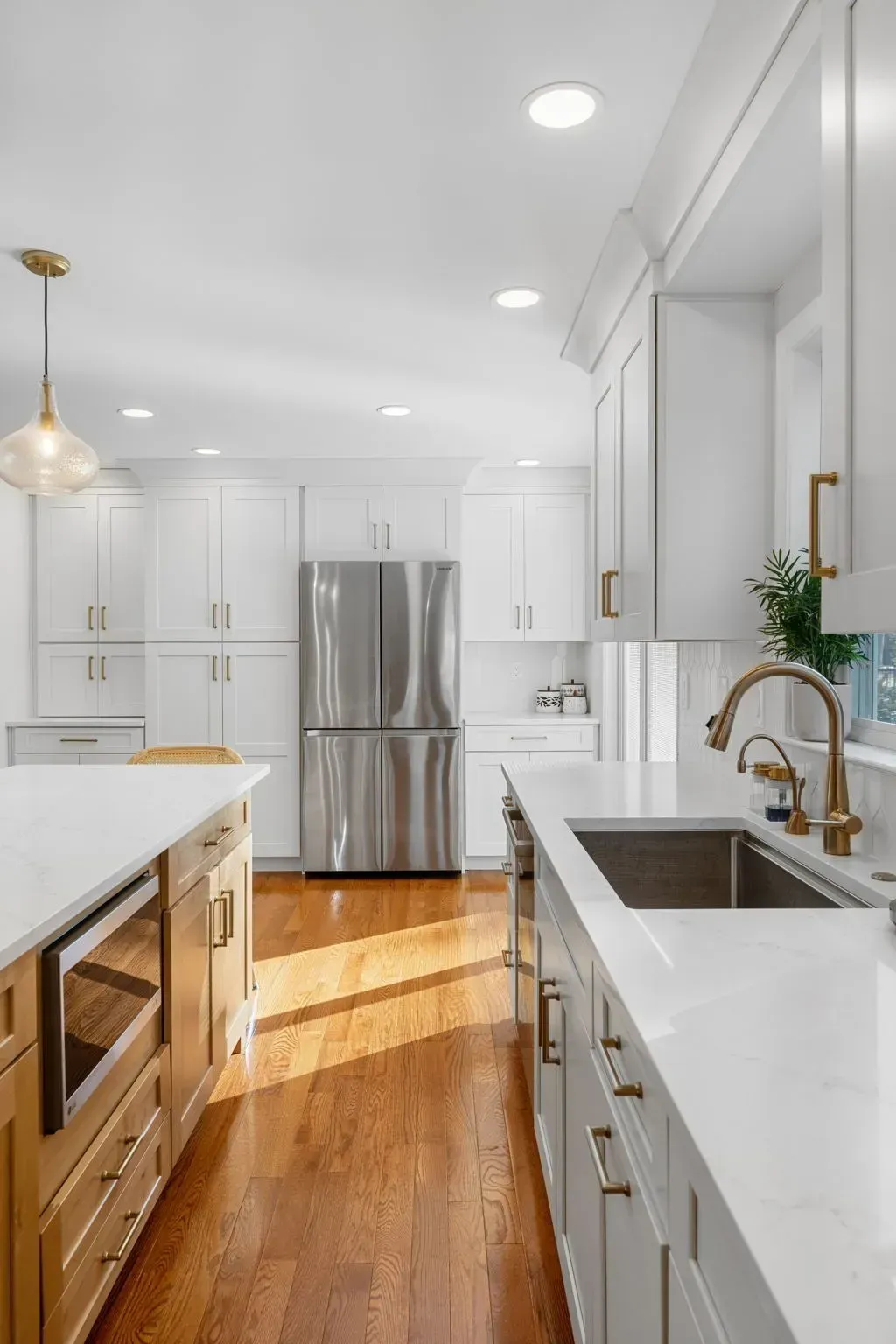 Bright white kitchen with stainless steel fridge, island, and sunlit hardwood floors In Bucks County PA