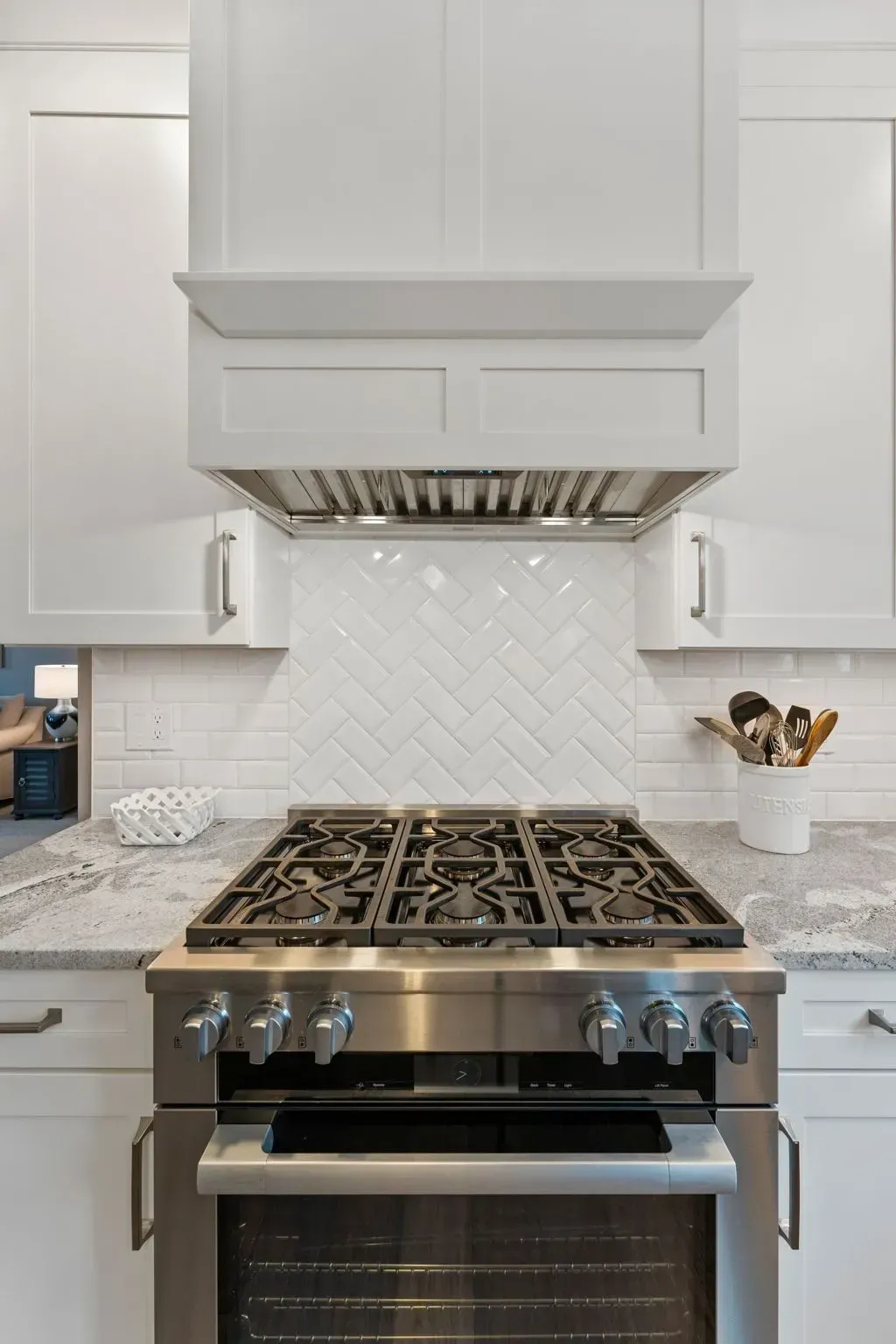 Modern white kitchen with a stainless gas range and marble backsplash In Bucks Country PA